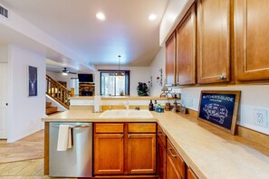 A kitchen with wooden cabinets, a stainless steel sink, and a chalkboard with a butcher's guide.