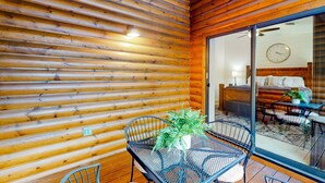 L’intérieur d’un chalet en bois comprend un coin repas, un lit et une horloge bien visible.