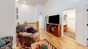 Un salon comprenant un canapé, une table basse, un téléviseur et un meuble en bois.