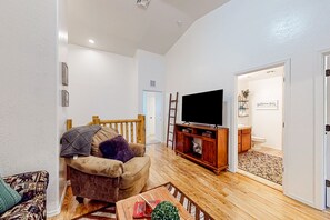 Una sala de estar con un sofá, una mesa de centro, un televisor y un mueble de madera.