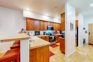 Eine moderne Küche mit Holzausstattung, Edelstahlgeräten und einer Bar.