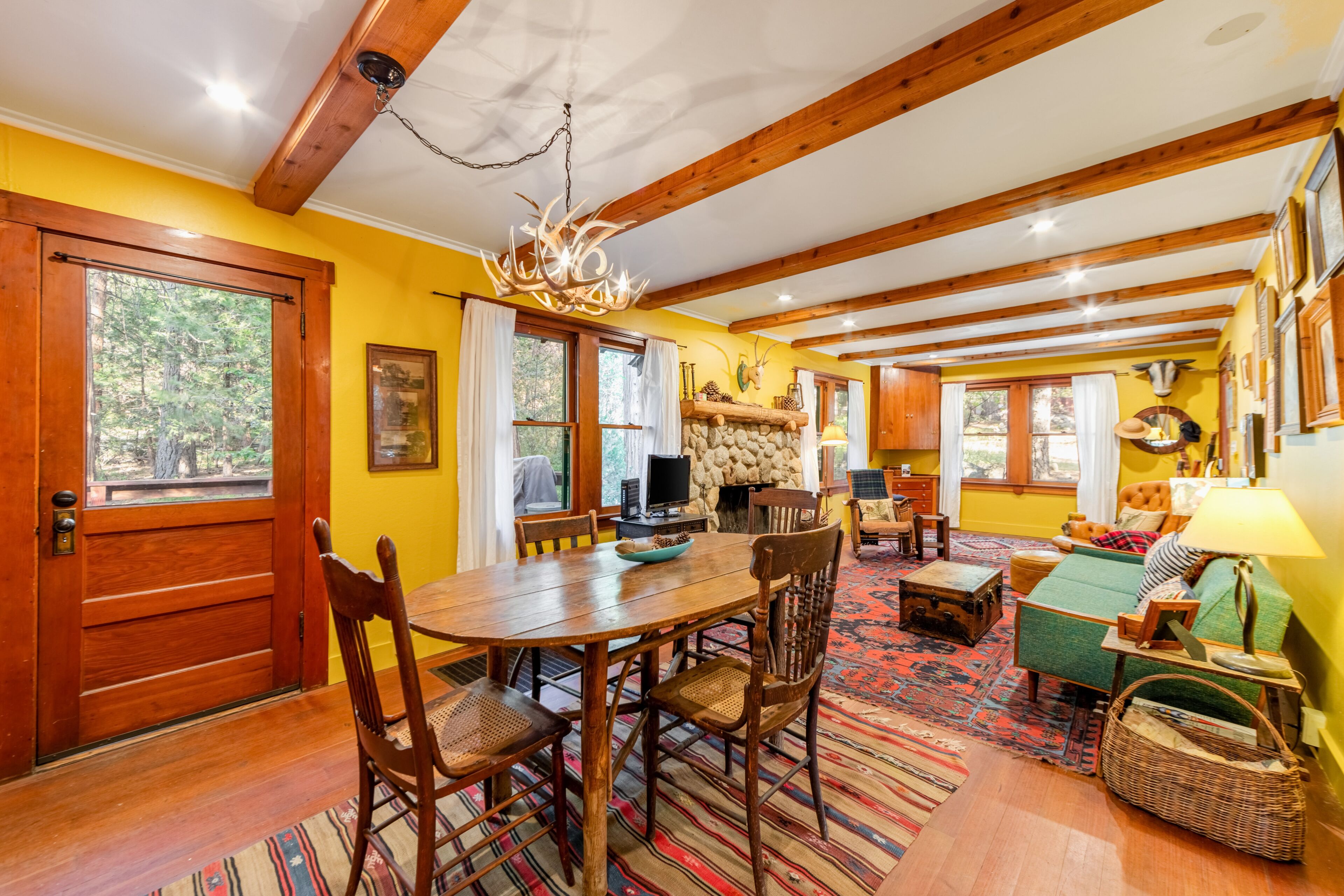 Um interior acolhedor com uma mesa de jantar de madeira, cadeiras, lareira e um sofá.