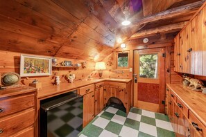Eine gemütliche Landhausküche mit Holzschränken, einem karierten Boden und einem kleinen Spülbecken.