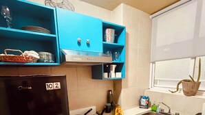 Eine kleine Küche mit einem schwarzen Kühlschrank, einem weißen Herd und blauen Schränken.