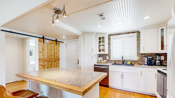 A modern kitchen with white cabinets, a granite countertop island, and a wooden ceiling. - Palm Desert Resorter | New Furnishings | 20 Pools, Championship Golf (Palm Desert)
