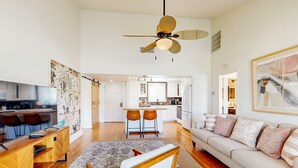 A spacious living area with a wooden coffee table, a sofa with decorative pillows, a dining area with chairs, and a kitchen in the background. - Palm Desert Resorter | New Furnishings | 20 Pools, Championship Golf (Palm Desert)