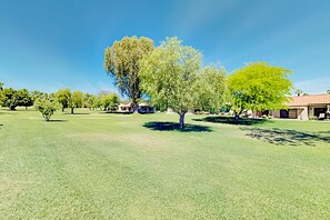 A grassy area with trees and a building in the background. - Palm Desert Resorter | New Furnishings | 20 Pools, Championship Golf (Palm Desert)