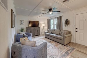 A living room with a ceiling fan, a sofa, a chair, a lamp, and a large window with curtains. -  Nice 2bed for mid term. Close to Joplin hospitals. Utilities and wifi included. (Joplin)