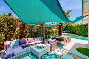 A patio area with a sofa, a coffee table, and a pool. - Centrally located home with private pool & hot tub, alfresco dining & firepit (Palm Springs)