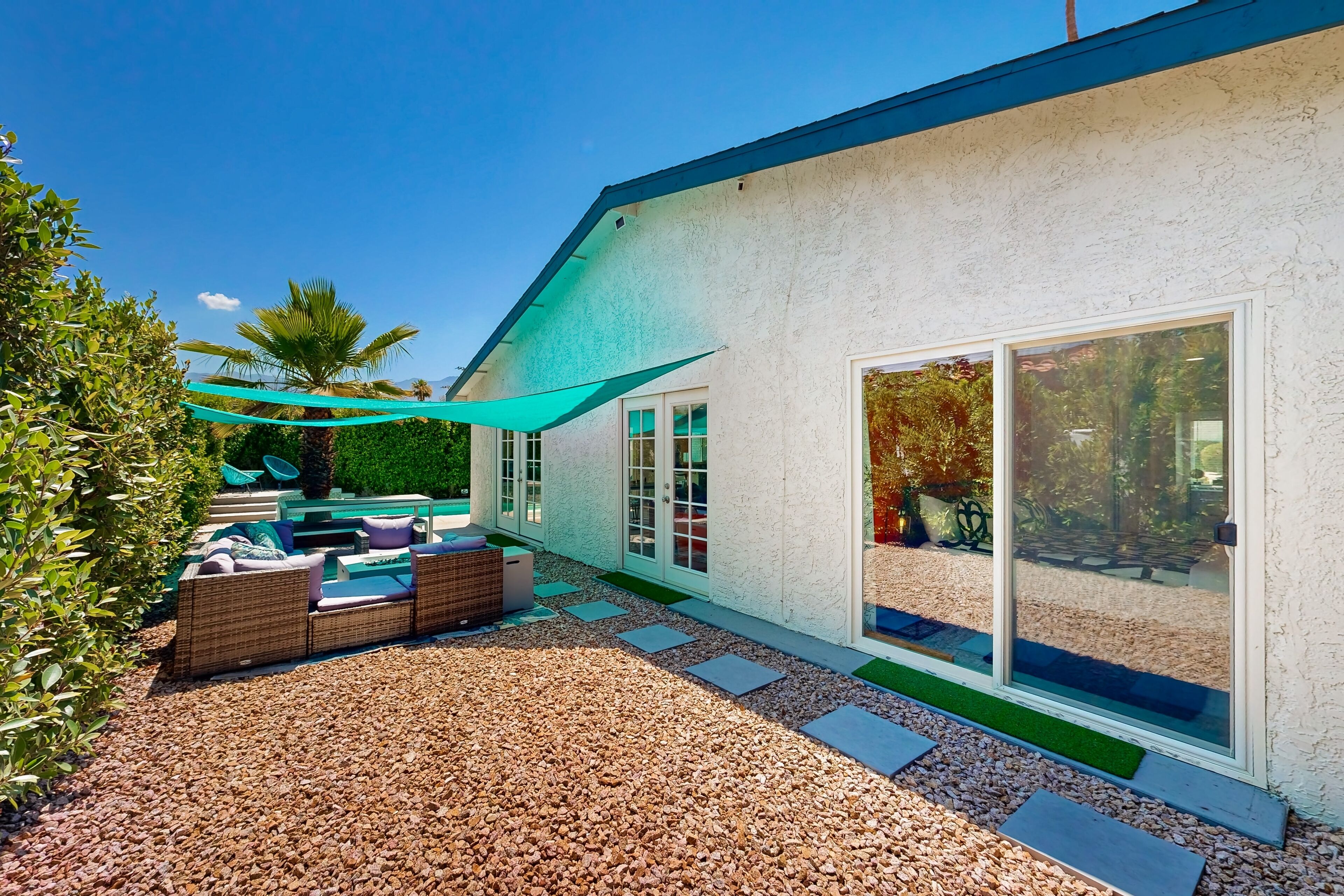 A modern outdoor patio with a seating area, a pergola, and a view of the surrounding landscape.