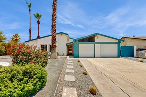 A modern two-story house with a garage, surrounded by a well-maintained garden and palm trees. - Centrally located home with private pool & hot tub, alfresco dining & firepit (Palm Springs)