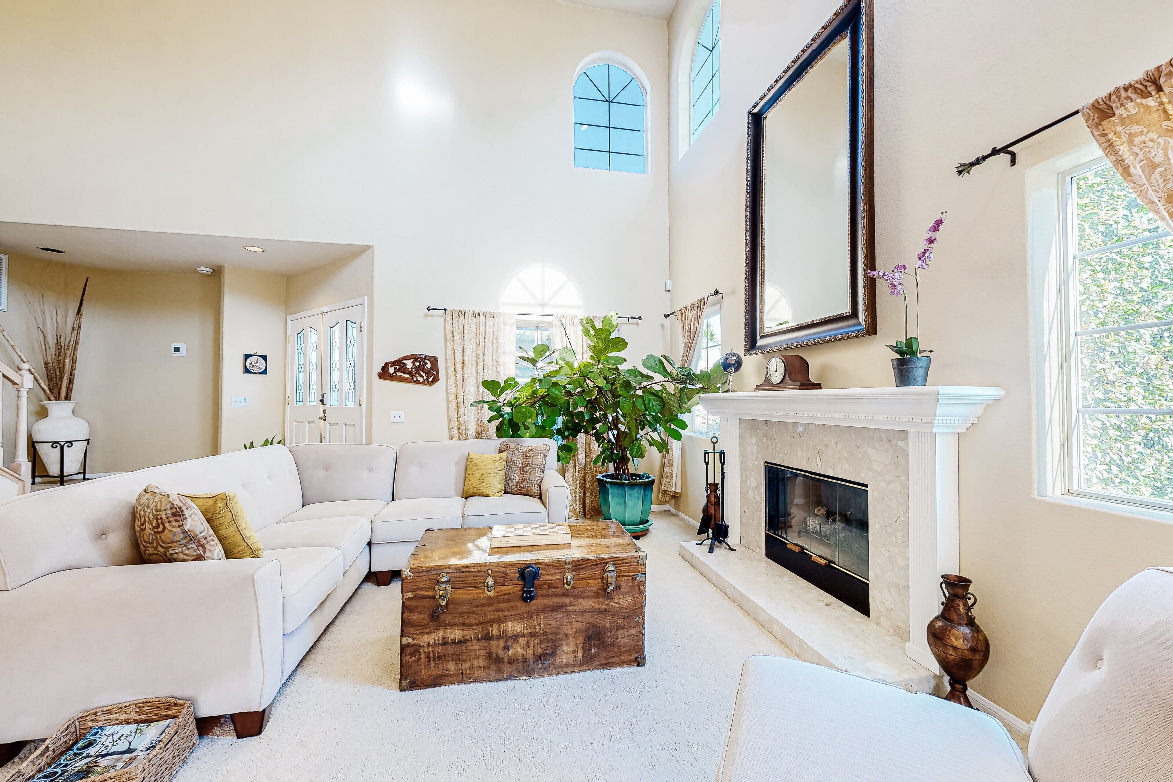 A spacious living room with a white sofa, a wooden chest, and a fireplace.