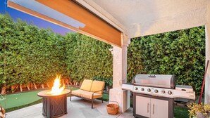 Une terrasse extérieure avec un foyer, un barbecue et un fauteuil rembourré.