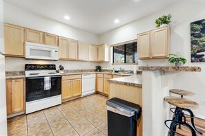 A kitchen with wooden cabinets, a microwave, an oven, a dishwasher, a trash bin, and a bar stool. - Peaceful retreat with covered porch, washer/dryer - golf/hiking (Pinetop)