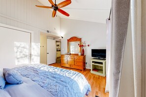 A bedroom with a bed, wooden dresser, TV stand, and a ceiling fan. - Sunlit dog-friendly home with central AC, deck, & fireplace - near golf & trails (Flagstaff)
