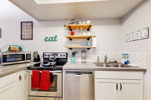 A modern kitchen with white cabinets, stainless steel appliances, and a coffee menu on the wall. - Sunlit dog-friendly home with central AC, deck, & fireplace - near golf & trails (Flagstaff)