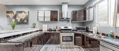 Una cocina moderna con una isla central, electrodomésticos de acero inoxidable y un amplio ventanal que ofrece luz natural.