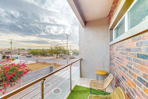 A balcony with a view of a street, a brick wall, and a small seating area with two chairs. - Stylish & modern dog-friendly townhome with lovely balcony - near parks & golf (Phoenix)
