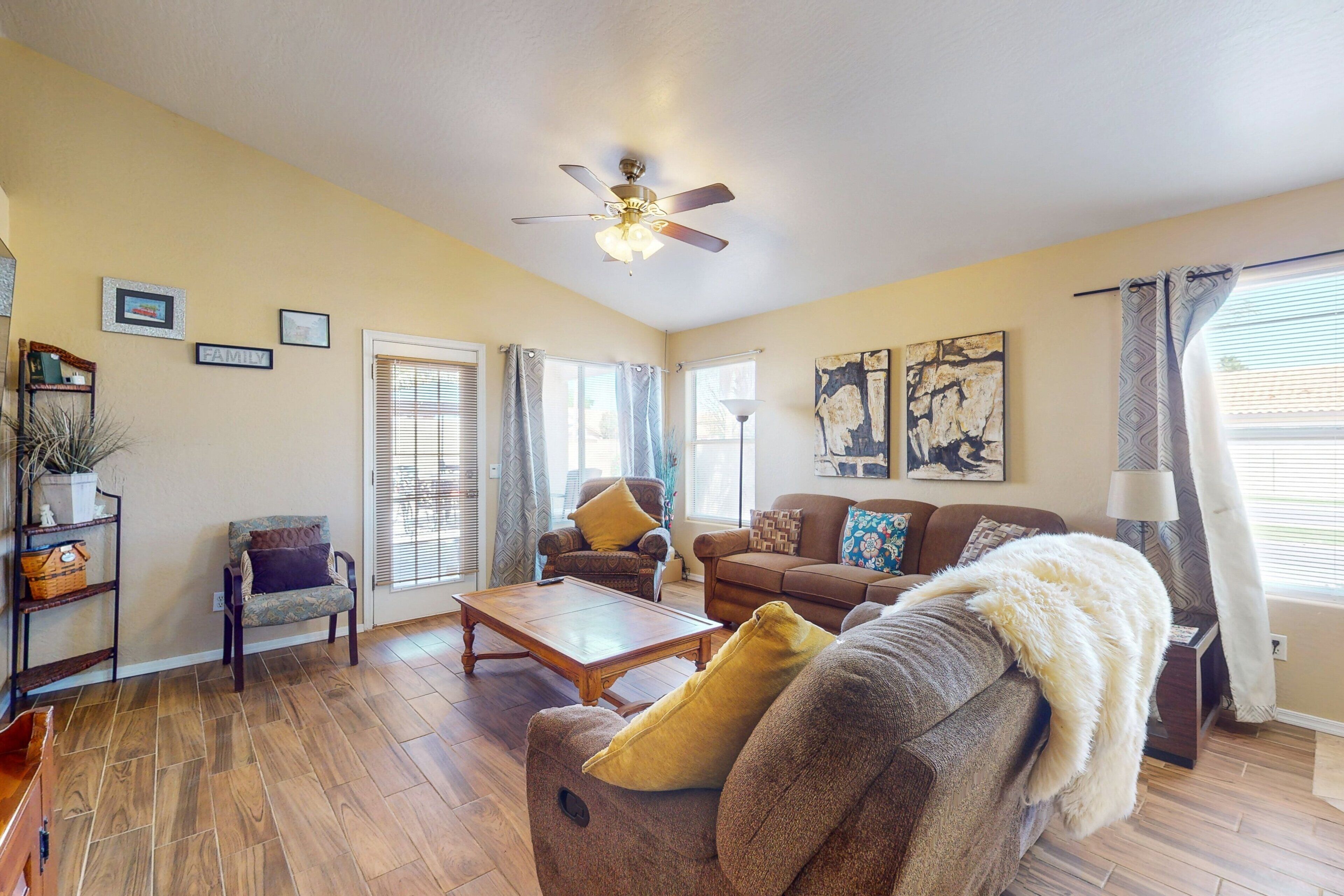 A living room with a ceiling fan, a sofa, a coffee table, and a fireplace.