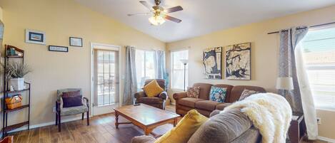 A living room with a ceiling fan, a sofa, a coffee table, and a fireplace.