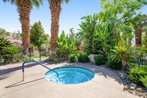 A swimming pool surrounded by tropical plants and palm trees.