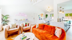 A modern living room with a sofa, chairs, a coffee table, and a neon sign. - Dog-friendly desert dream with a private pool, pool spa, & putting green (Palm Springs)