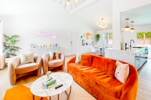 Ein modernes Wohnzimmer mit einer Couch, Sesseln, einem Couchtisch und einer Neonreklame.