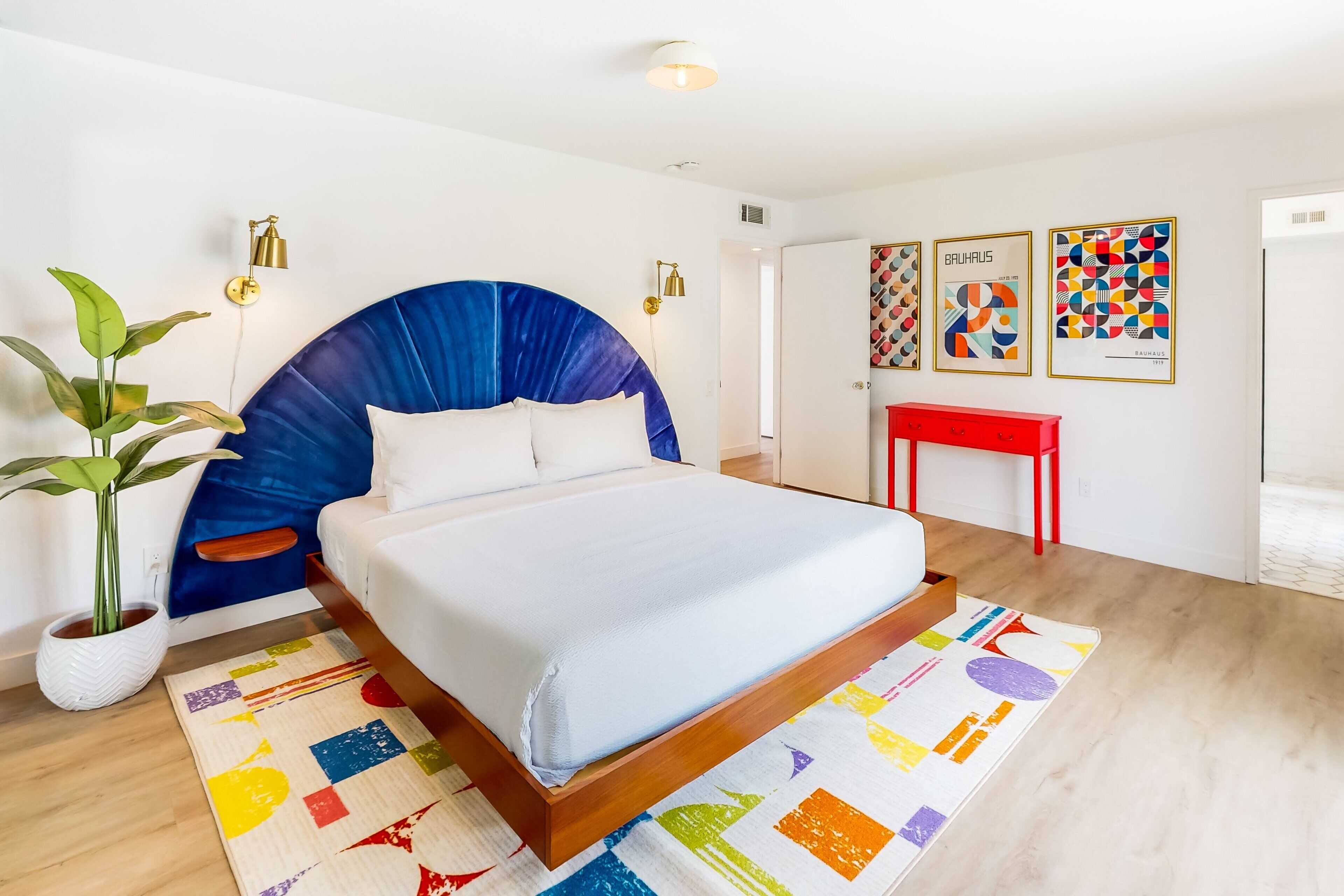 Un dormitorio moderno con una cama grande, una planta en maceta y una alfombra colorida.