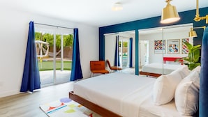A modern bedroom with a large bed, a chair, and a view of the outdoors. - Dog-friendly desert dream with a private pool, pool spa, & putting green (Palm Springs)