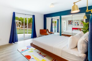 Ein modernes Schlafzimmer mit einem großen Bett, einem Sessel und Blick ins Freie.