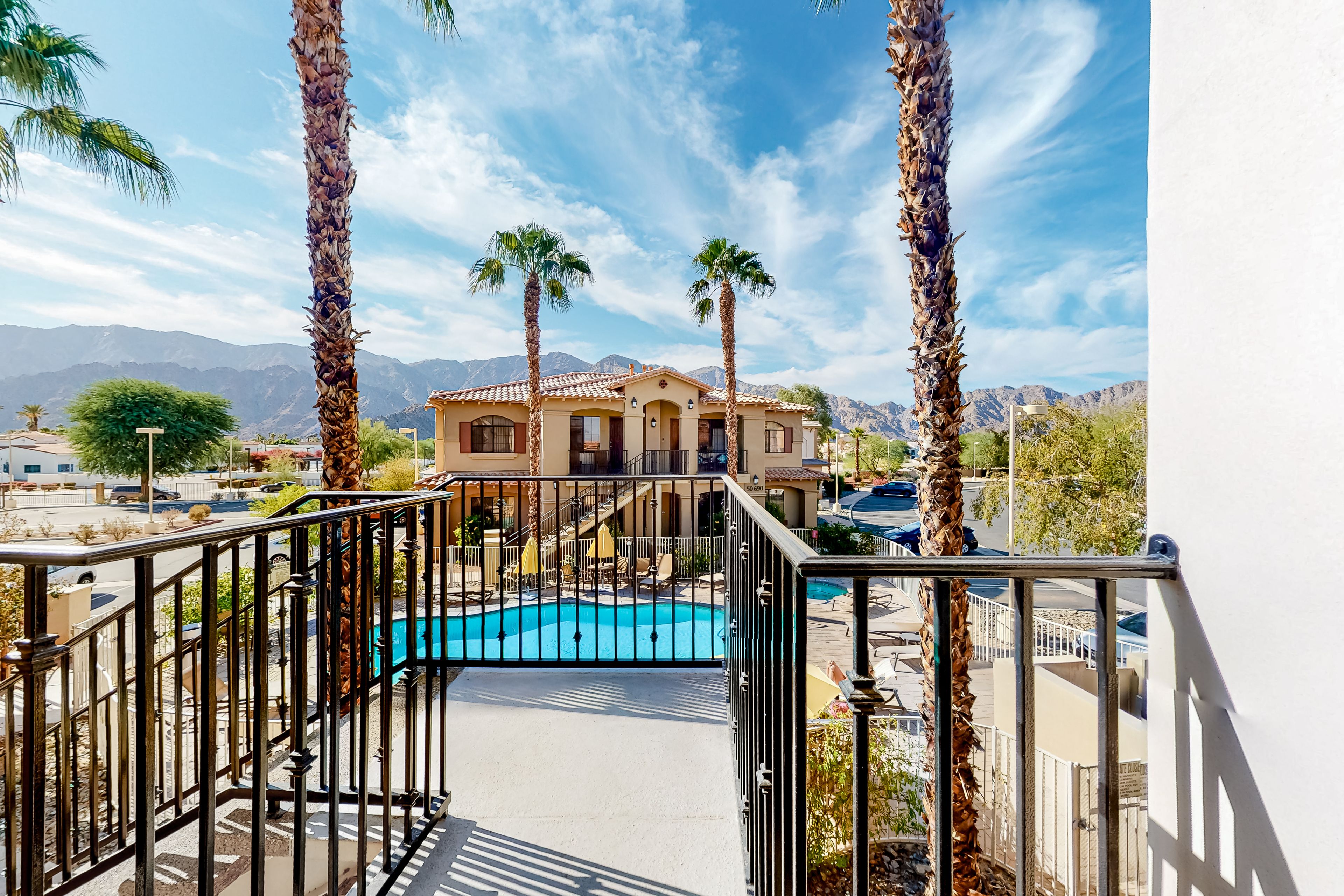 A pool area with a view of a building and mountains in the background.