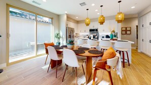Une cuisine moderne avec des meubles blancs, un îlot central et des luminaires suspendus.