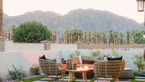 Un espace extérieur aménagé avec des chaises en osier et une table, offrant une vue sur un paysage montagneux.