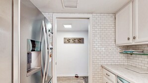 Eine moderne Küche mit weißen Schränken, einem Edelstahlkühlschrank und einem Holzboden.