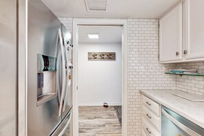 Een moderne keuken met witte kasten, een roestvrijstalen koelkast en een houten vloer.