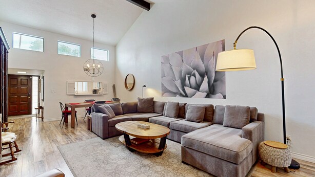 Ein großzügiges Wohnzimmer mit einem geräumigen Ecksofa, einem runden Couchtisch und einer modernen Stehlampe.
