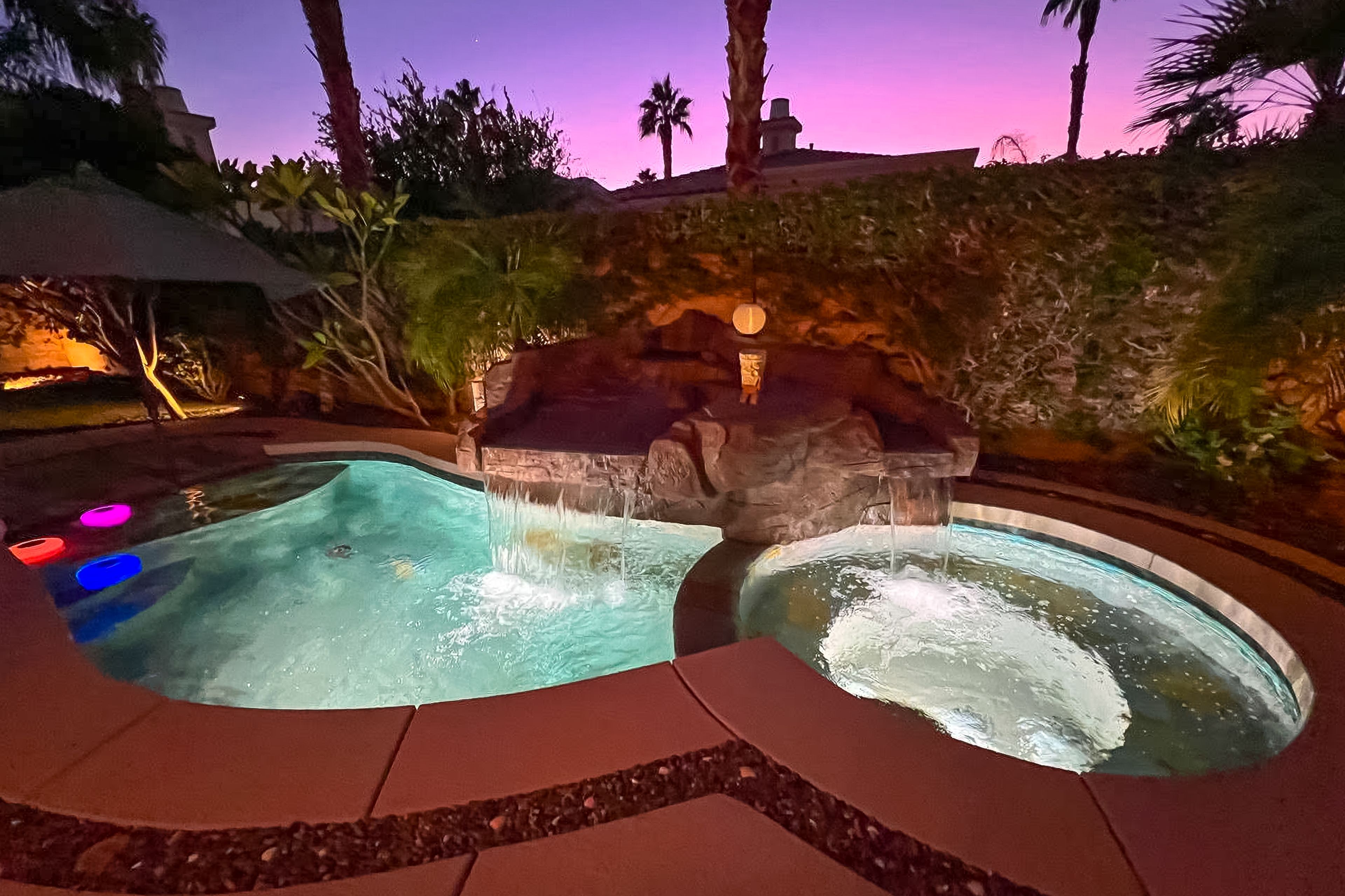 A hot tub area with two hot tubs and a waterfall feature.