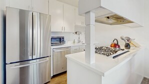 Een moderne keuken met roestvrijstalen apparatuur, witte kasten en een centraal eiland.