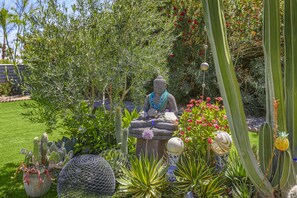 Un jardin agrémenté d’une statue de Bouddha, de différents types de cactus et de vases décoratifs.