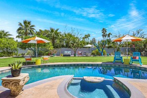 Une piscine à bord incurvé, entourée de palmiers et agrémentée de mobilier d’extérieur.