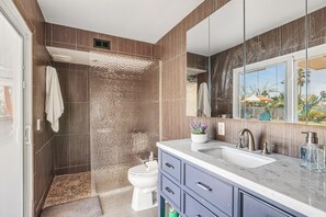 Une salle de bain moderne équipée d’une douche, de toilettes et d’un meuble-lavabo avec un grand miroir.