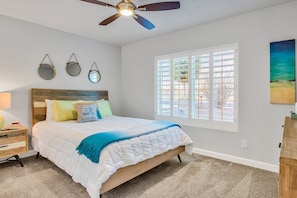 A bedroom with a bed, bedside tables, a ceiling fan, and a window with blinds. - Modern paradise with private pool, firepit, putting green, game room & AC (Scottsdale)