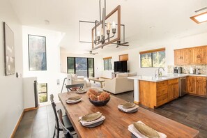 A modern kitchen with wooden cabinets, a large island, and a dining area with a wooden table and chairs. - Oak Creek Overlook: Views, Game Room, Gym (Sedona)