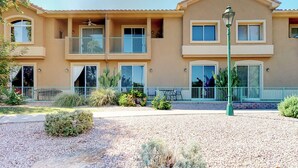 A multi-story residential building with balconies, a landscaped garden, and a street lamp. - Lakefront condo with private washer/dryer, central AC & heated pool (Mesa)