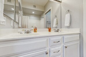 A bathroom with two sinks, a large mirror, and white cabinets.
