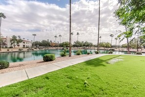 A landscaped area with a pool, palm trees, and a building in the background. - Lakefront condo with private washer/dryer, central AC & heated pool (Mesa)