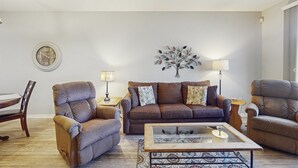 A living room with a brown sofa, two armchairs, a coffee table, a side table with a lamp, and a wall clock. - Lakefront condo with private washer/dryer, central AC & heated pool (Mesa)