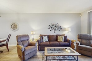 A living room with a brown sofa, two armchairs, a coffee table, a side table with a lamp, and a wall clock. - Lakefront condo with private washer/dryer, central AC & heated pool (Mesa)