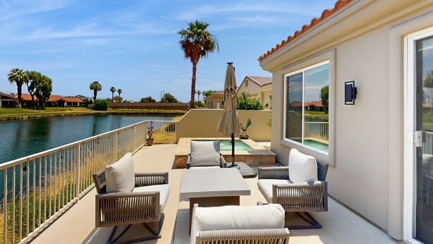 Un patio con mobiliario exterior, una piscina y vistas a un cuerpo de agua.