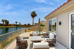 A patio with outdoor furniture, a pool, and a view of a body of water. - Spectacular lakefront & mountain views on the Pete Dye Dunes Golf Course (La Quinta)